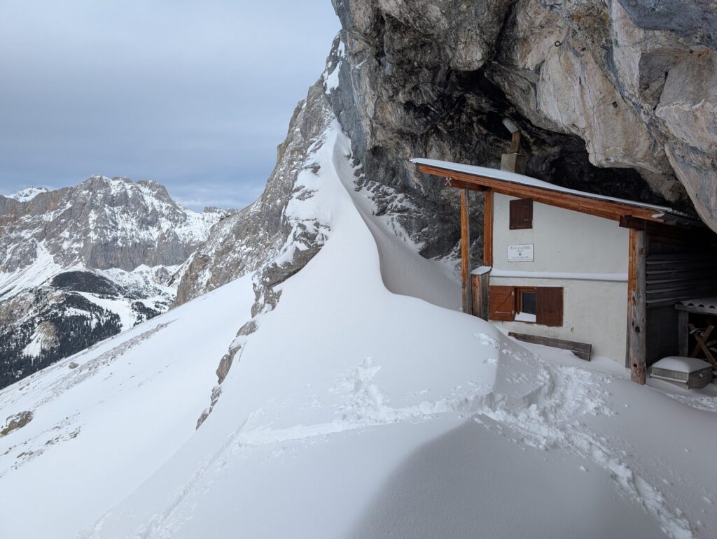 Breitenkopfhütte im Winter unter einem Felsvorsprung in der Mieminger Kette.