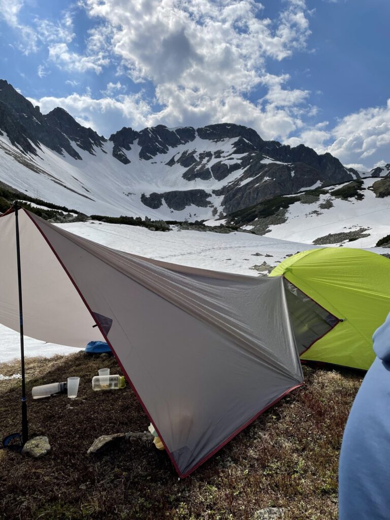 Tarp und Zelt mit verschneitem Kar im Hintergrund